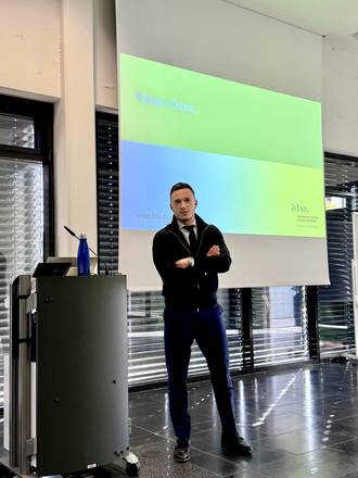 Ein Redner steht mit verschränkten Armen vor einer Projektionsfläche, auf der die Worte „Vielen Dank“ zu lesen sind.