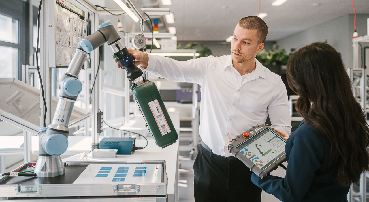 Zwei Studierende an einem Industrieroboter