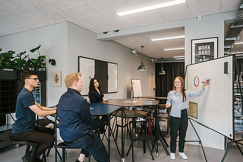 Studentin präsentiert etwas an einem Whiteboard